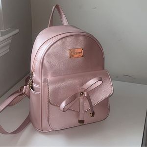 Adorable Pink mini backpack with gold accents and bow detail.